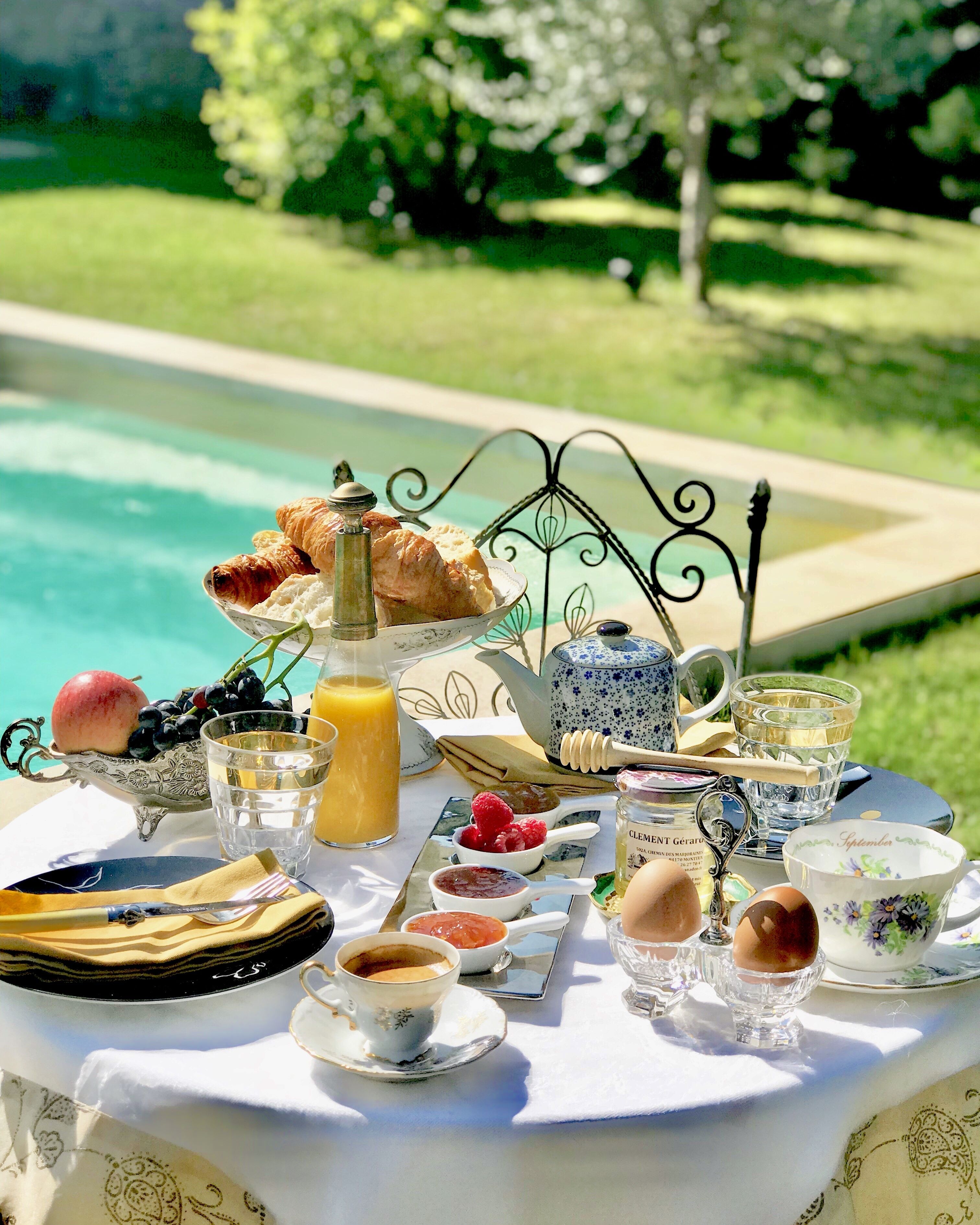 Ein Frühstückstisch mit Croissants, Obst, Honig, Marmelade und Eiern.
