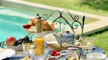 Ein Frühstückstisch mit Croissants, Obst, Honig, Marmelade und Eiern.