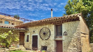 Un bâtiment en pierre avec un toit en tuiles, une grande roue et une cheminée.