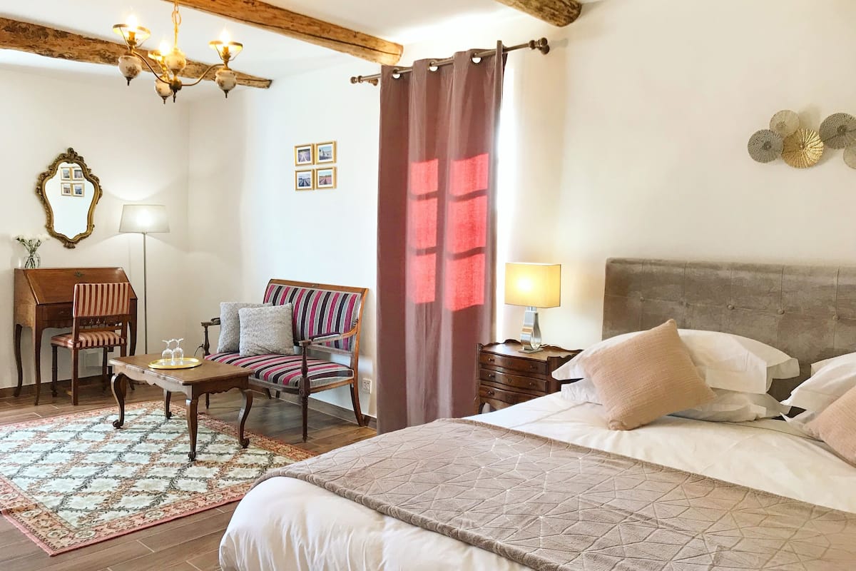 Une chambre à coucher comprenant un lit, un bureau, une chaise, une lampe et un ventilateur de plafond.