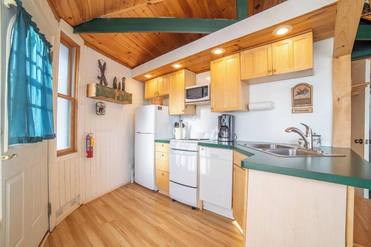 A compact kitchen with wooden cabinets, a microwave, a coffee maker, and a sink.
