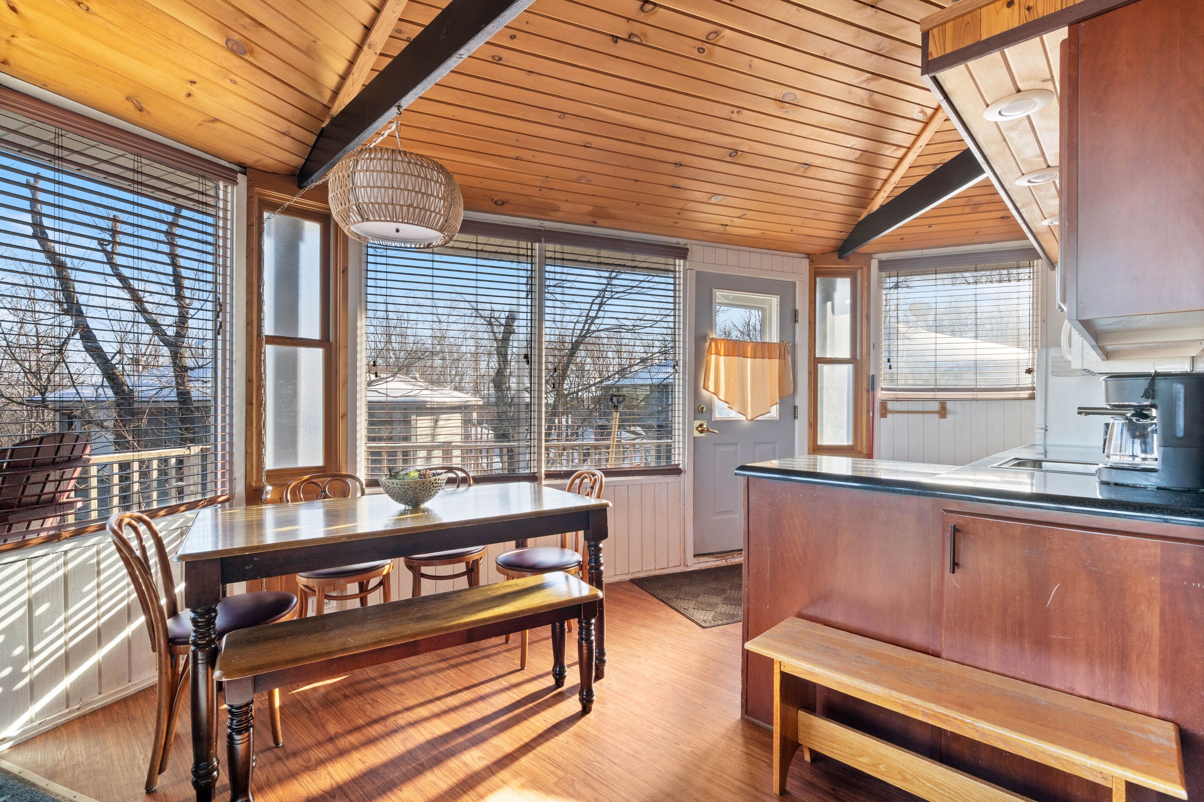 A wooden interior with a dining table, chairs, and a bench.