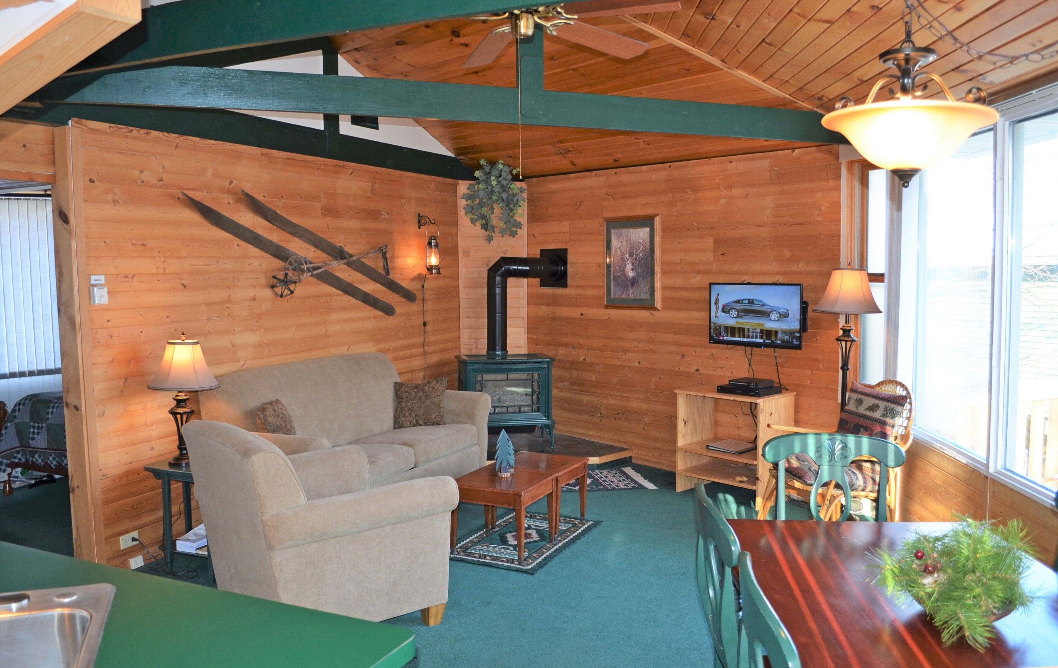 L’intérieur chaleureux d’un chalet en bois comprend un canapé, une table, un téléviseur, une cheminée et une fenêtre donnant sur un paysage agréable.
