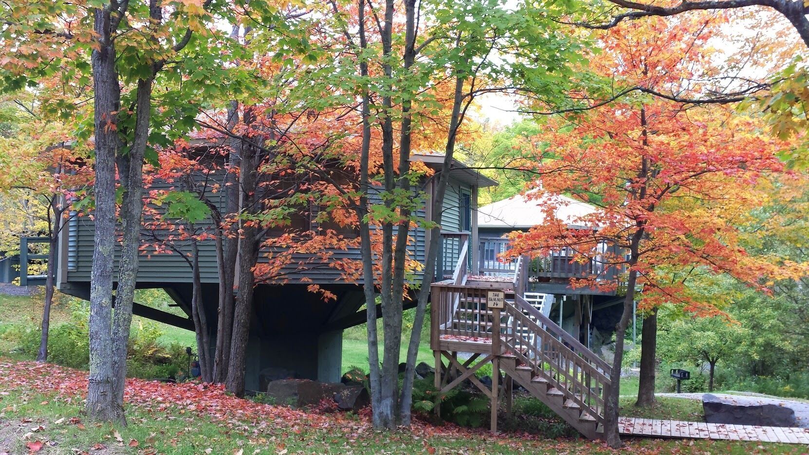 A wooden cabin with a covered entrance and a wooden staircase leading to a deck.