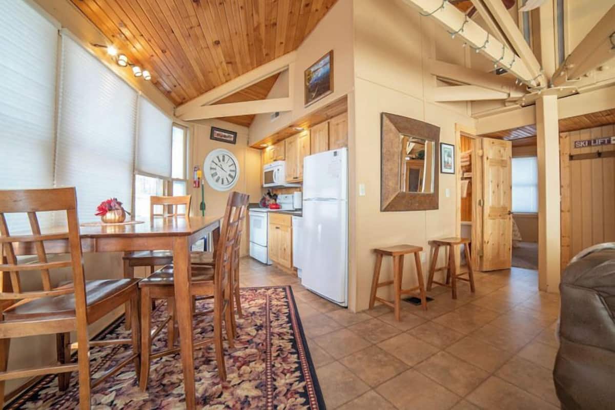 A spacious kitchen with wooden cabinets, a white refrigerator, and a clock on the wall.
