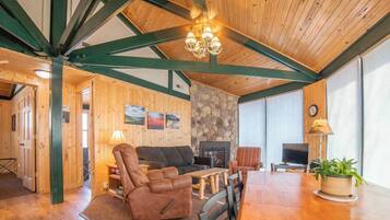 Una sala de estar acogedora con chimenea, vigas de madera y pared de piedra.