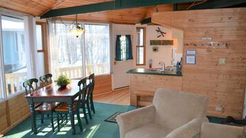 Interior de una cabaña de madera con comedor, cocina y una sala de estar acogedora.