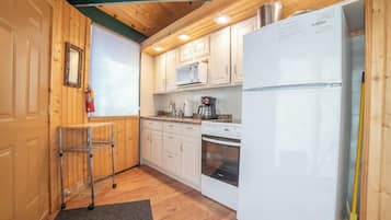 Una cocina compacta con armarios blancos, un refrigerador de acero inoxidable, un microondas y un horno.
