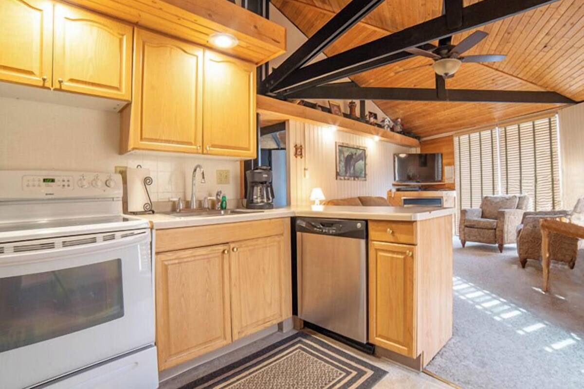 A modern kitchen with wooden cabinets, a white stove, and a dishwasher.
