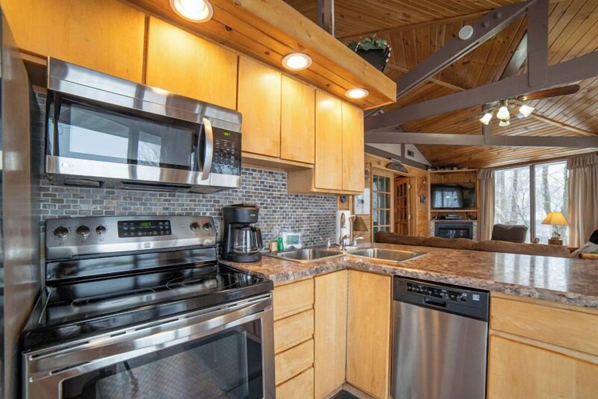 A modern kitchen with stainless steel appliances, wooden cabinets, and a granite countertop.