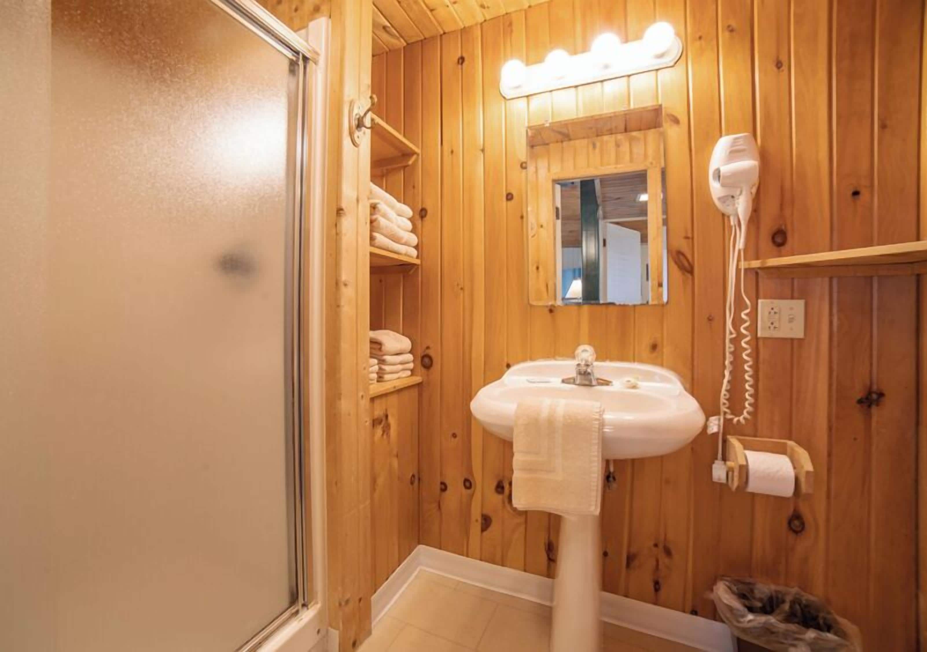 A wooden bathroom with a sink, towel rack, and a hairdryer.