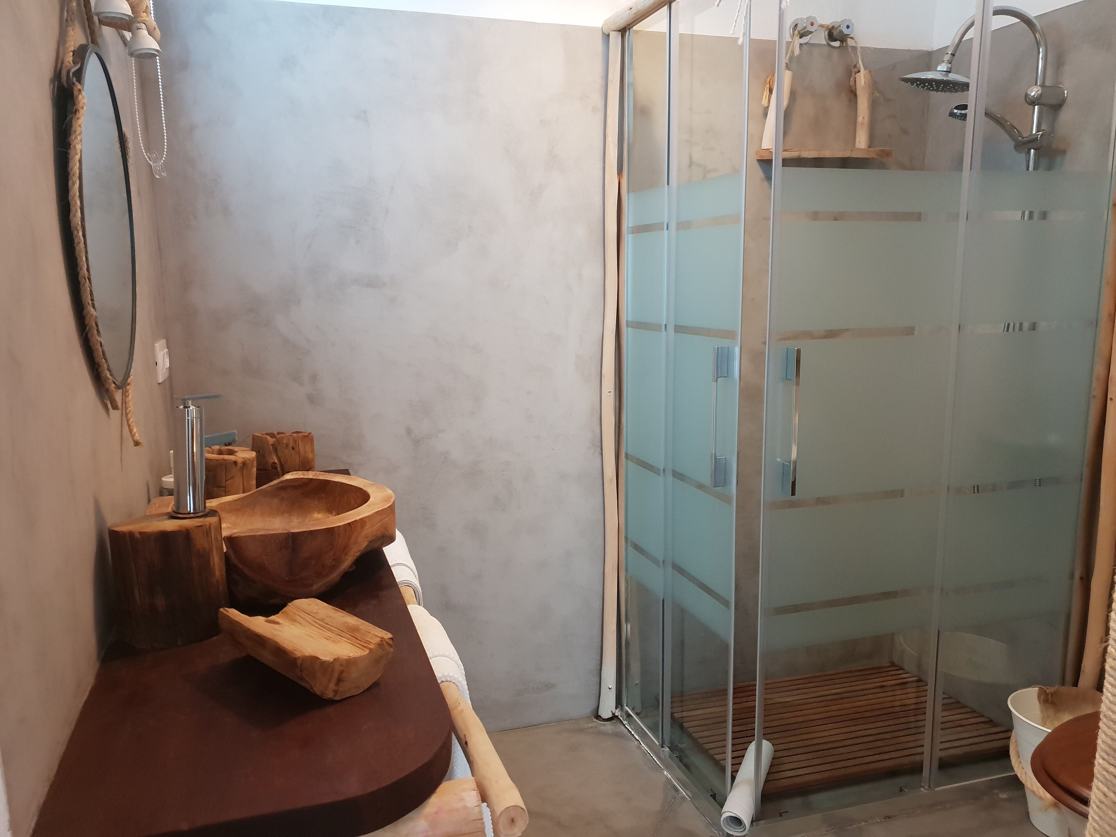 Un baño con tocador de madera, cabina de ducha con paredes de vidrio y un perchero para toallas.