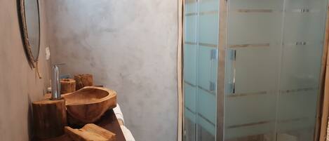 Un baño con tocador de madera, cabina de ducha con paredes de vidrio y un perchero para toallas.