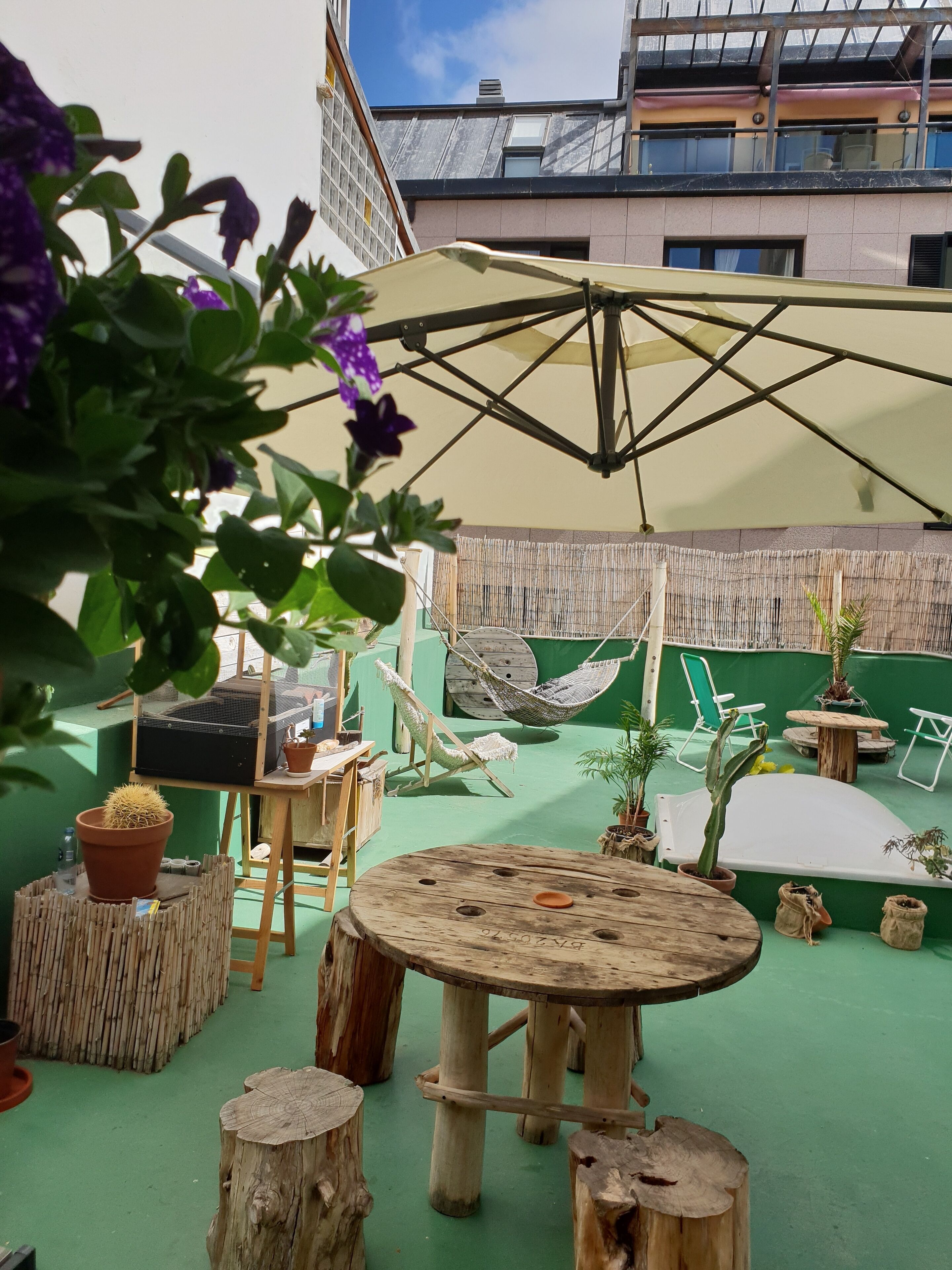 An outdoor patio area with a round wooden table, a hammock, and a large umbrella.