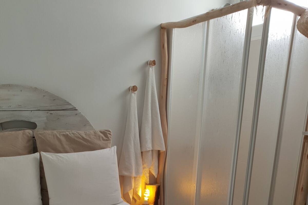 Een bed met witte lakens, een bedlampje en een houten hoofdbord.