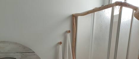 Un lit avec du linge de lit blanc, une lampe de chevet et une tête de lit en bois.