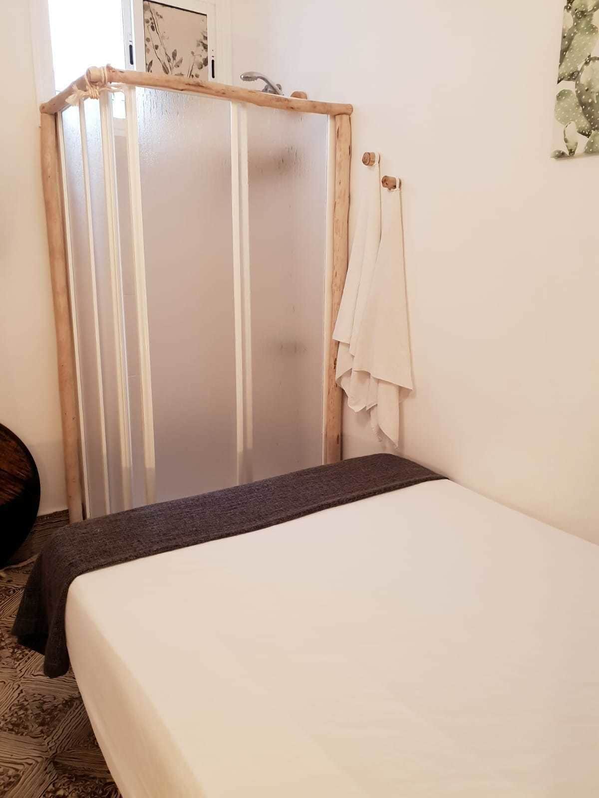 A bedroom with a bed, a wooden wardrobe, and a mirror.