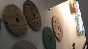 Una escalera con barandilla de madera y una pared decorada con varias obras de arte de madera.