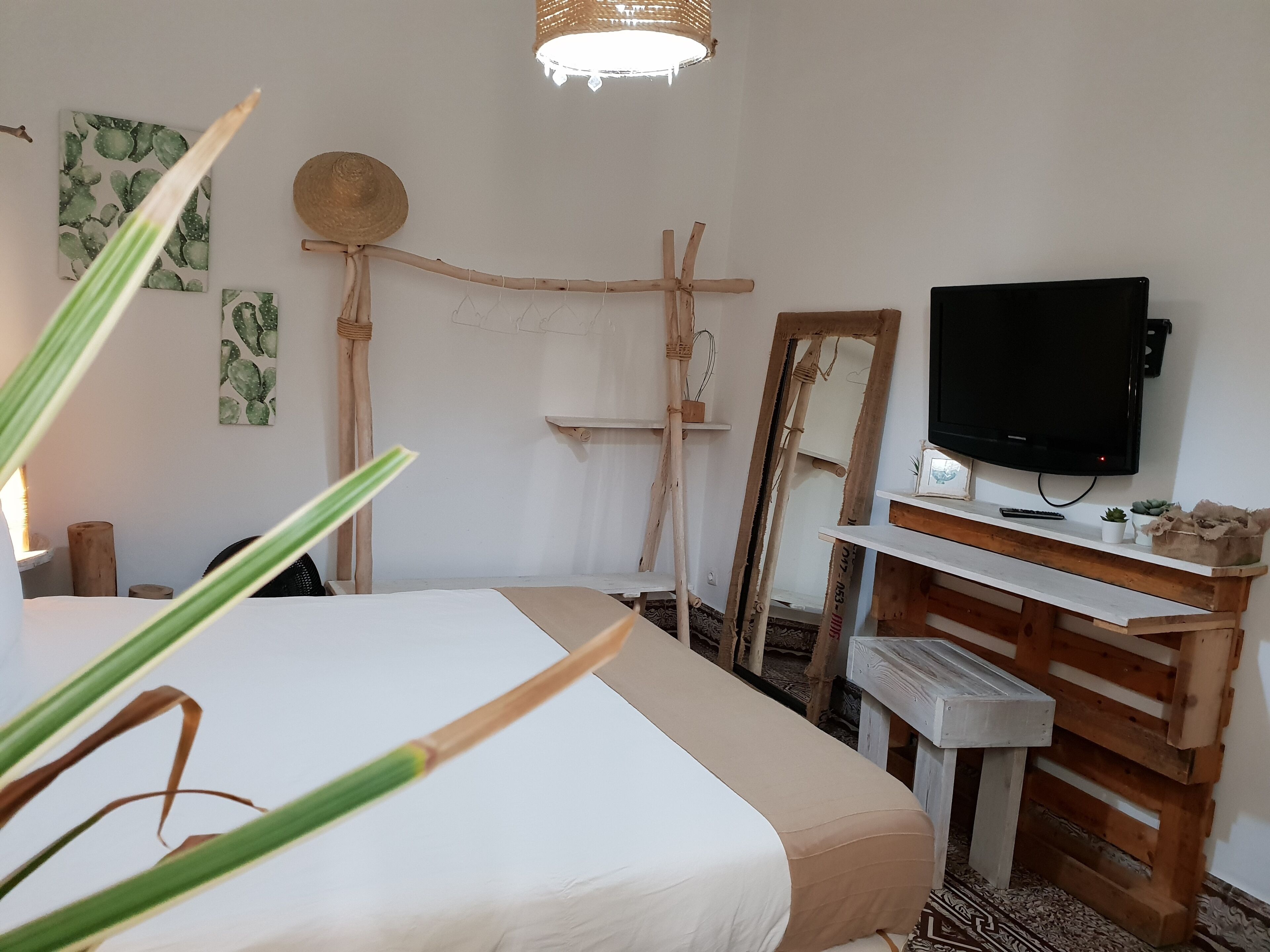 Une chambre à coucher comprenant un lit, un bureau en bois, une télévision et des œuvres d’art murales.