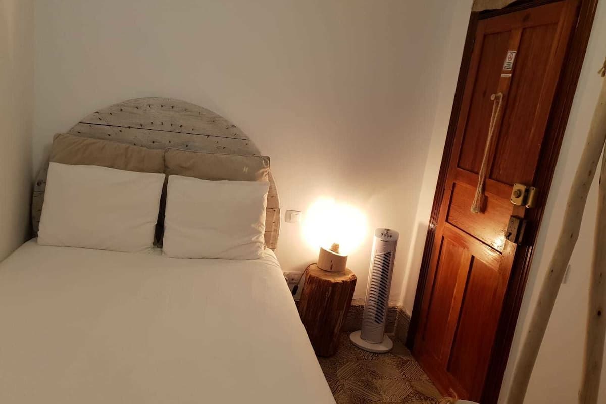 Een slaapkamer met een bed, een bedlamp, een verwarming en een houten kledingkast.