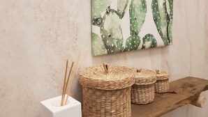Una estantería de madera con tres cestas tejidas y una caja blanca con ramitas de junco.
