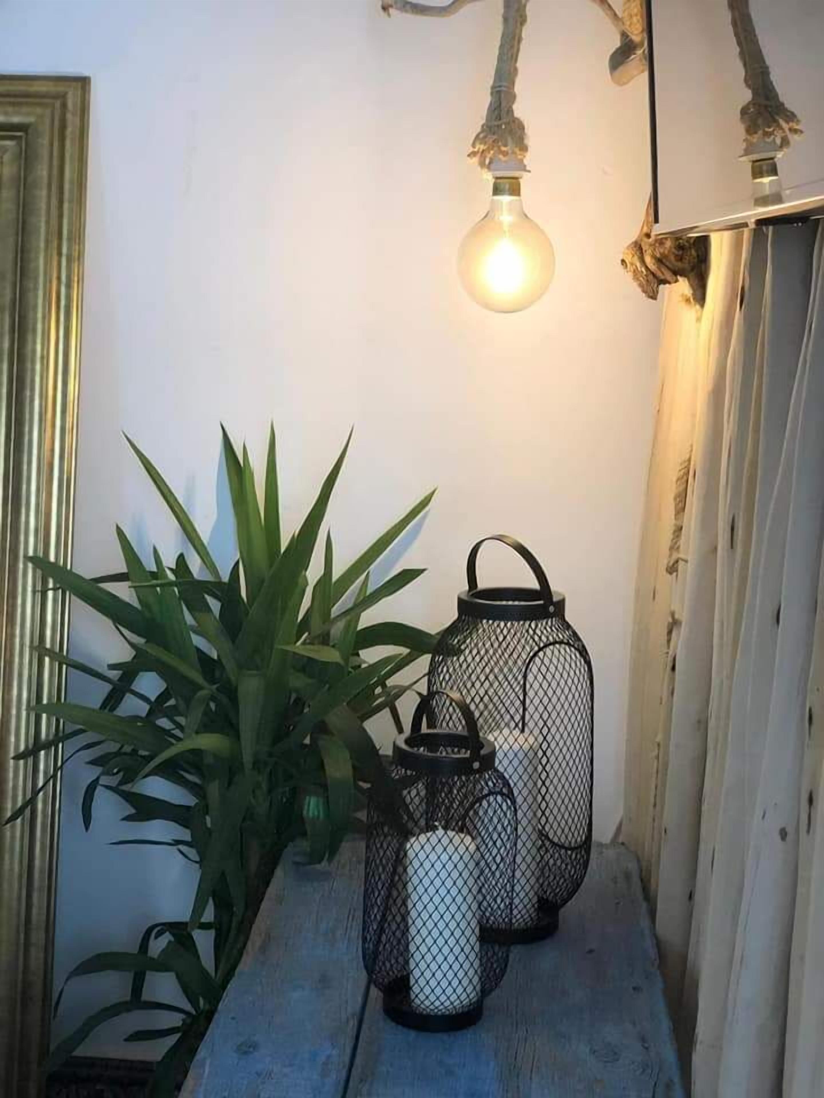 A wooden shelf with a potted plant and two black lanterns.