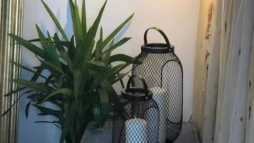 A wooden shelf with a potted plant and two black lanterns.