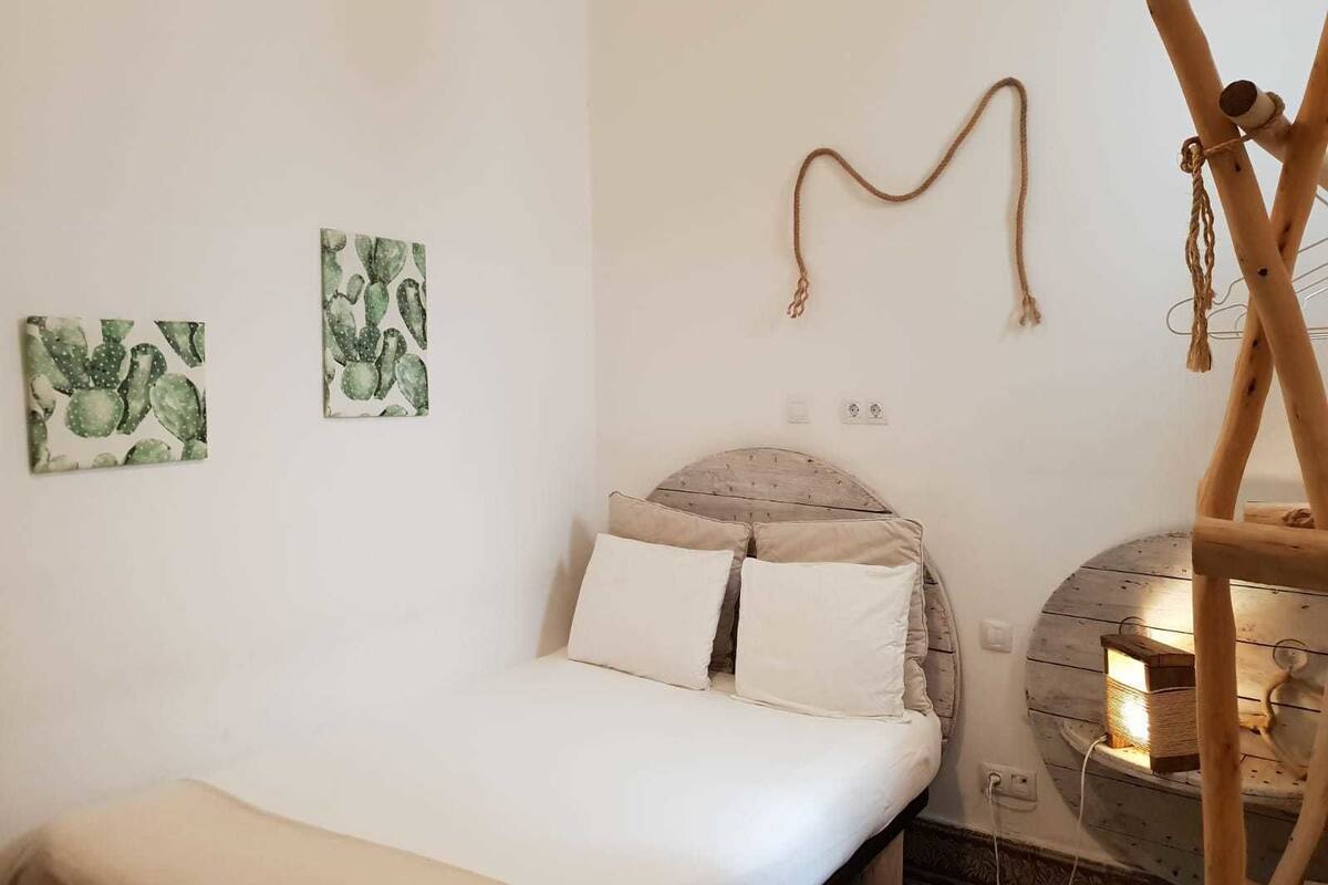 Een slaapkamer met een bed, twee kunstwerken aan de muur, een houten hoofdbord en een klein houten constructie met verlichting.