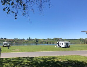 Un camping con un lago, zonas de césped y una carretera.