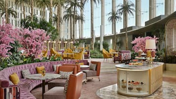 A spacious lobby with a curved seating area, a central serving station, and tall palm trees.
