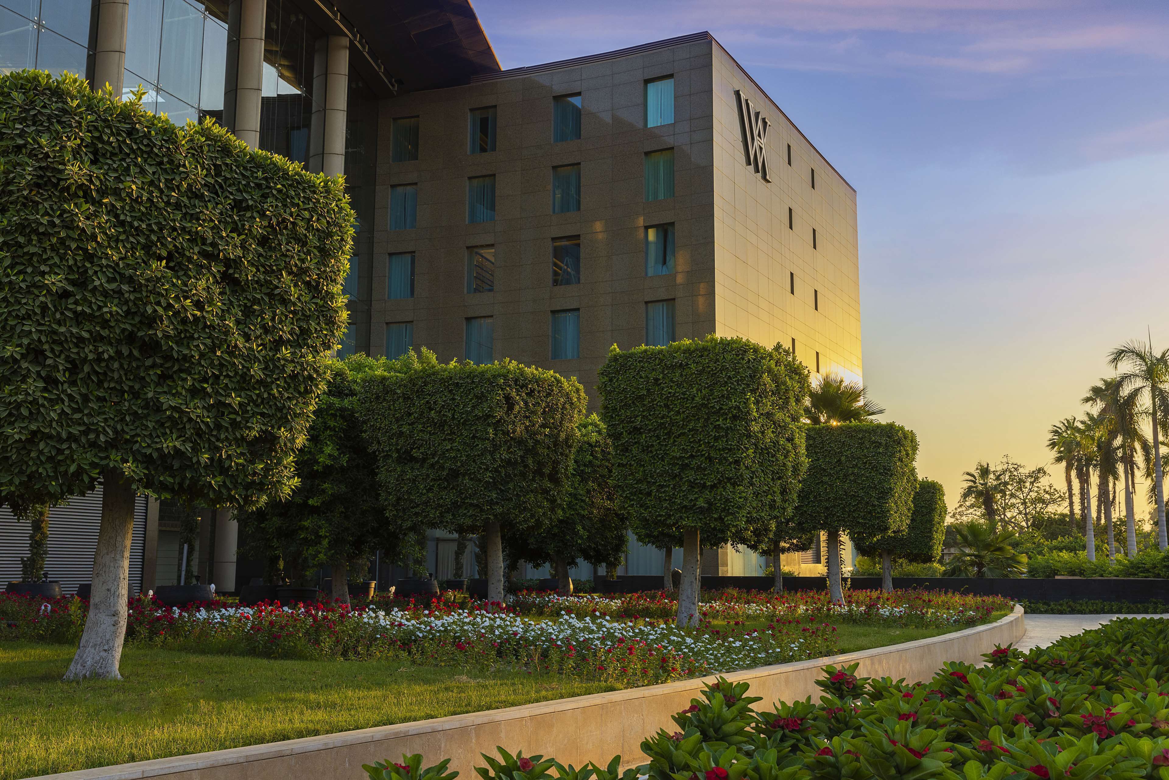 A modern building with a landscaped garden featuring neatly trimmed hedges and flower beds.