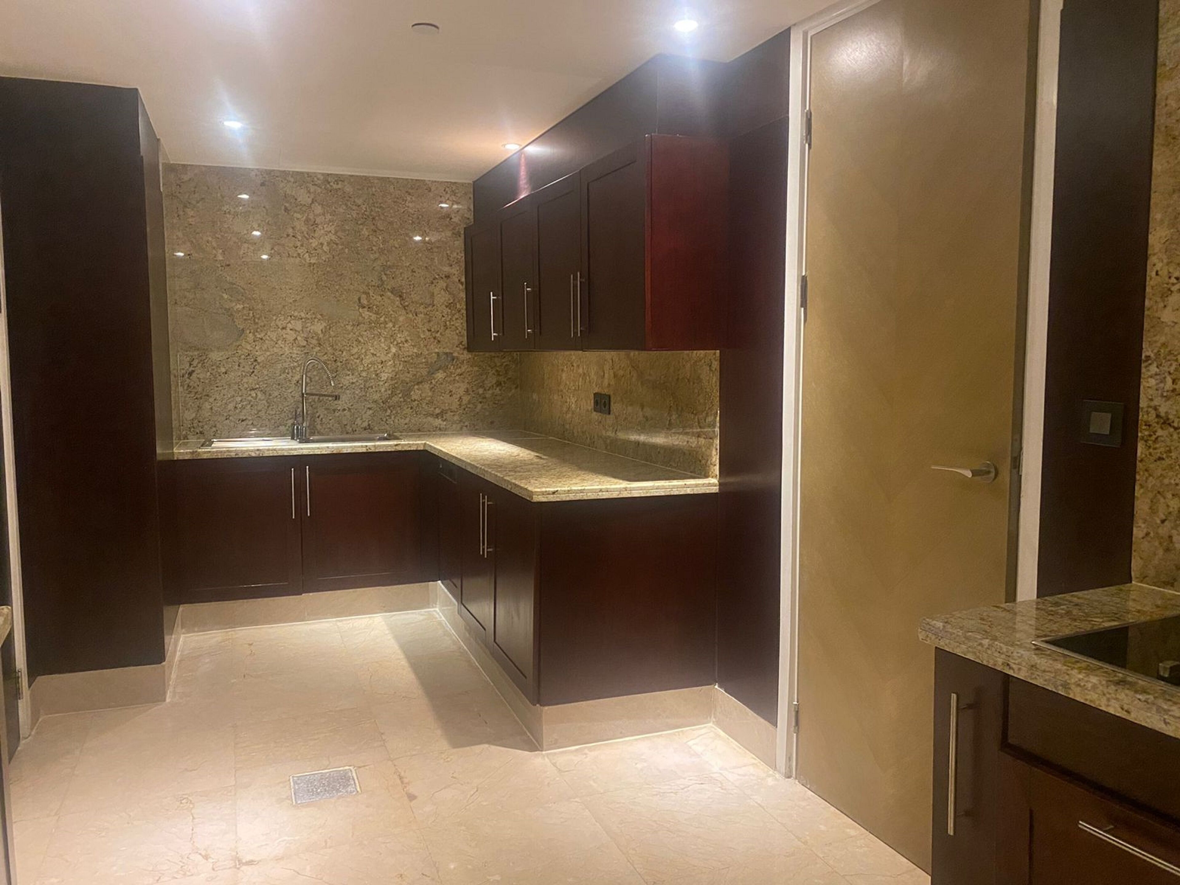 A compact kitchen with dark cabinetry, a granite countertop, and a marble backsplash.