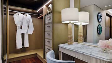 Habitación de hotel con vestidor, tocador de mármol y una lámpara moderna.
