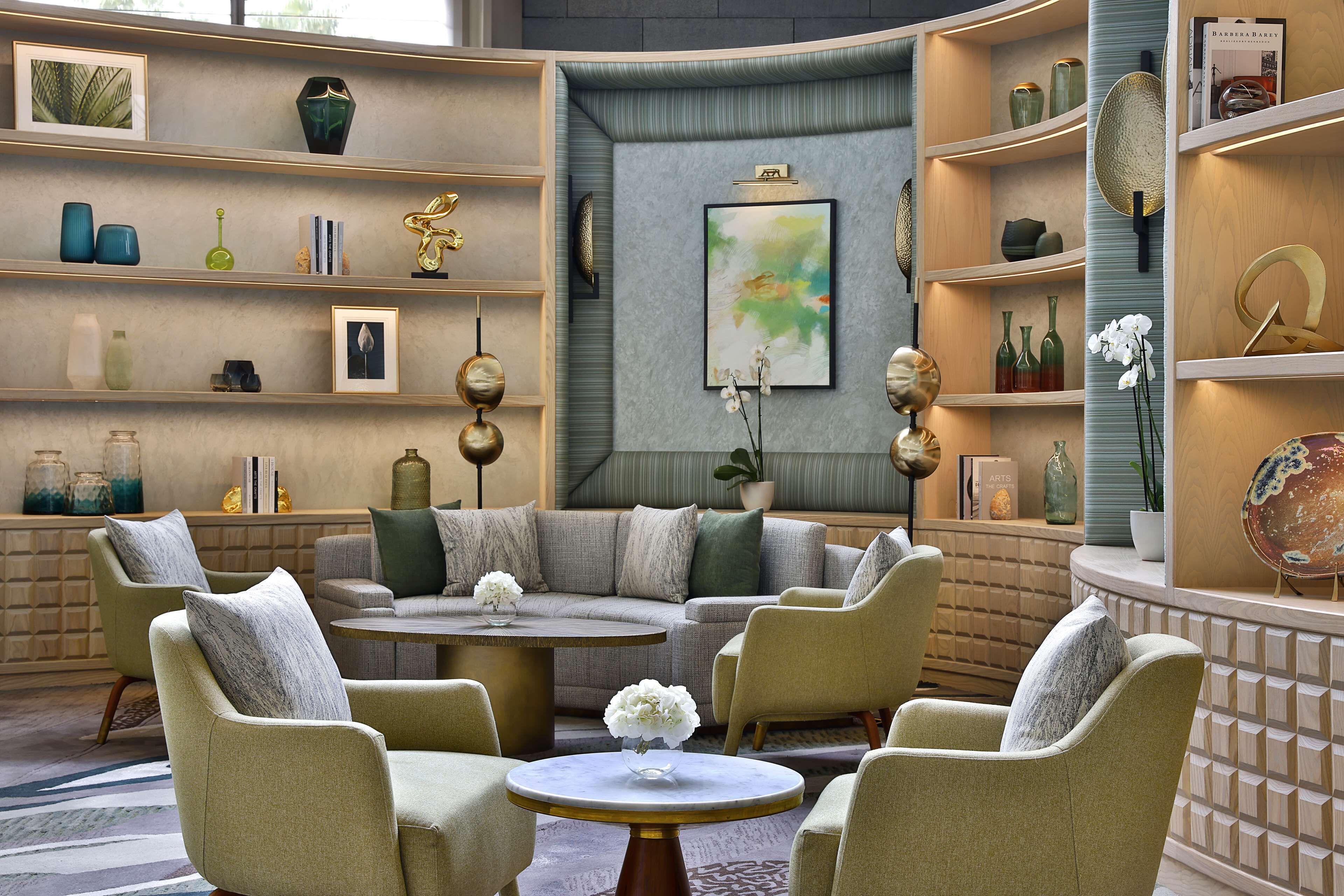 Una sala moderna con un sofá seccional, sillones, una mesa de centro y objetos decorativos en estanterías.