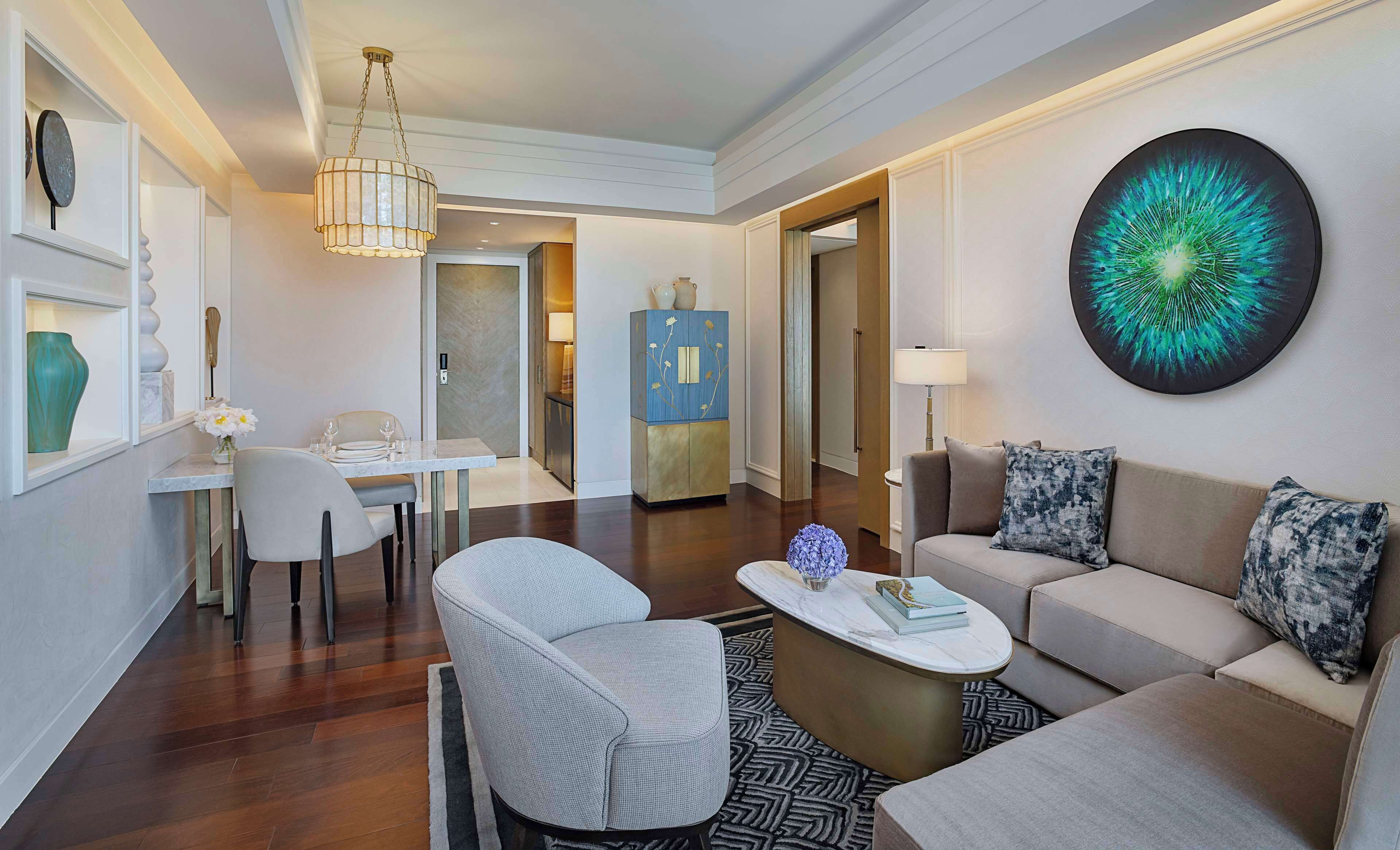 A modern living room with a sofa, two armchairs, a coffee table, and a dining area with a table and chairs.