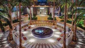 A spacious lobby with a central circular seating area, palm trees, and a geometric floor pattern. - Waldorf Astoria Cairo Heliopolis (Cairo)