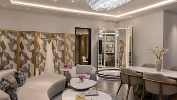 A modern hotel lobby with a curved seating area, a round table with a vase of flowers, and a decorative mirror.