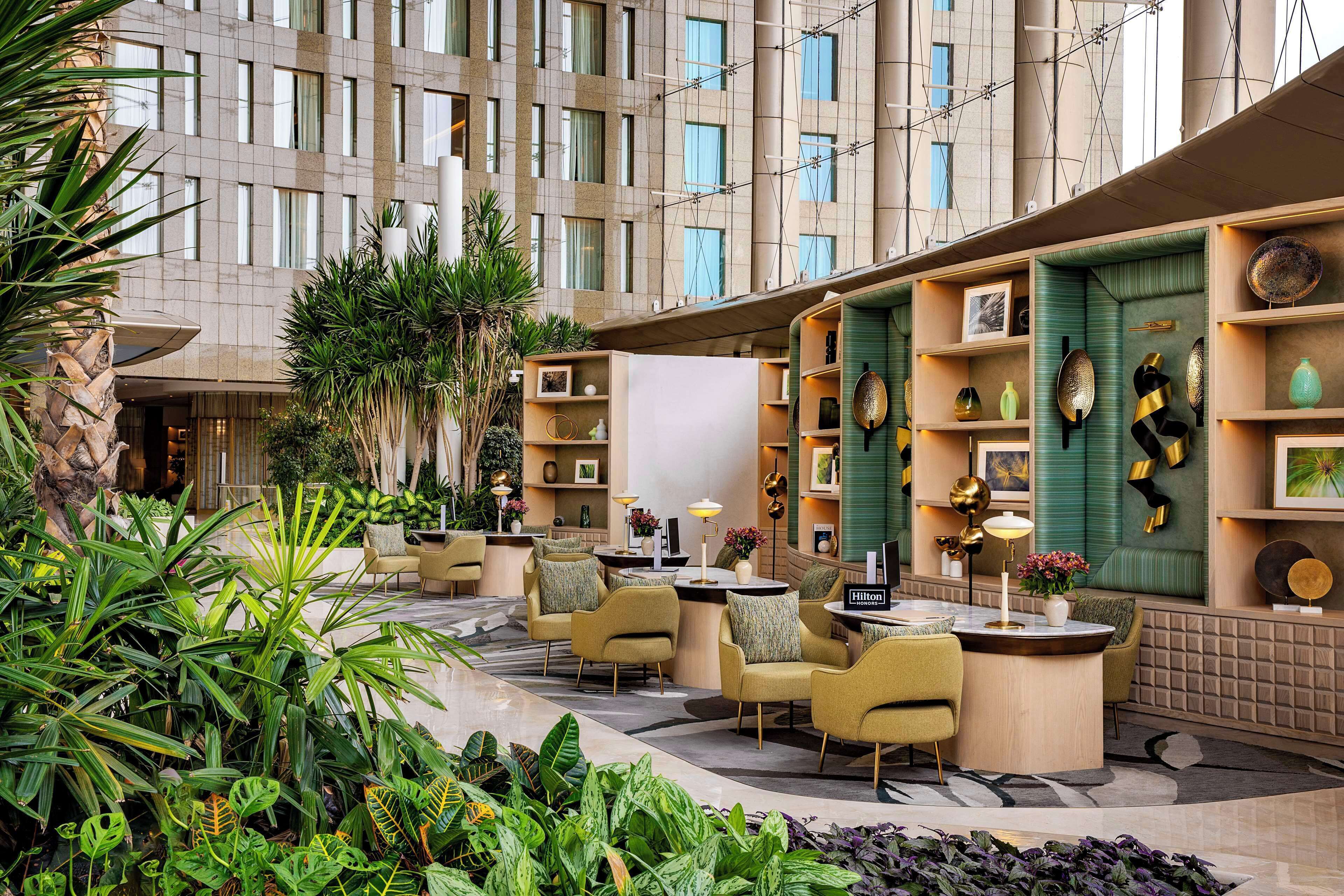 A hotel lobby with seating areas, plants, and a display of decorative items.