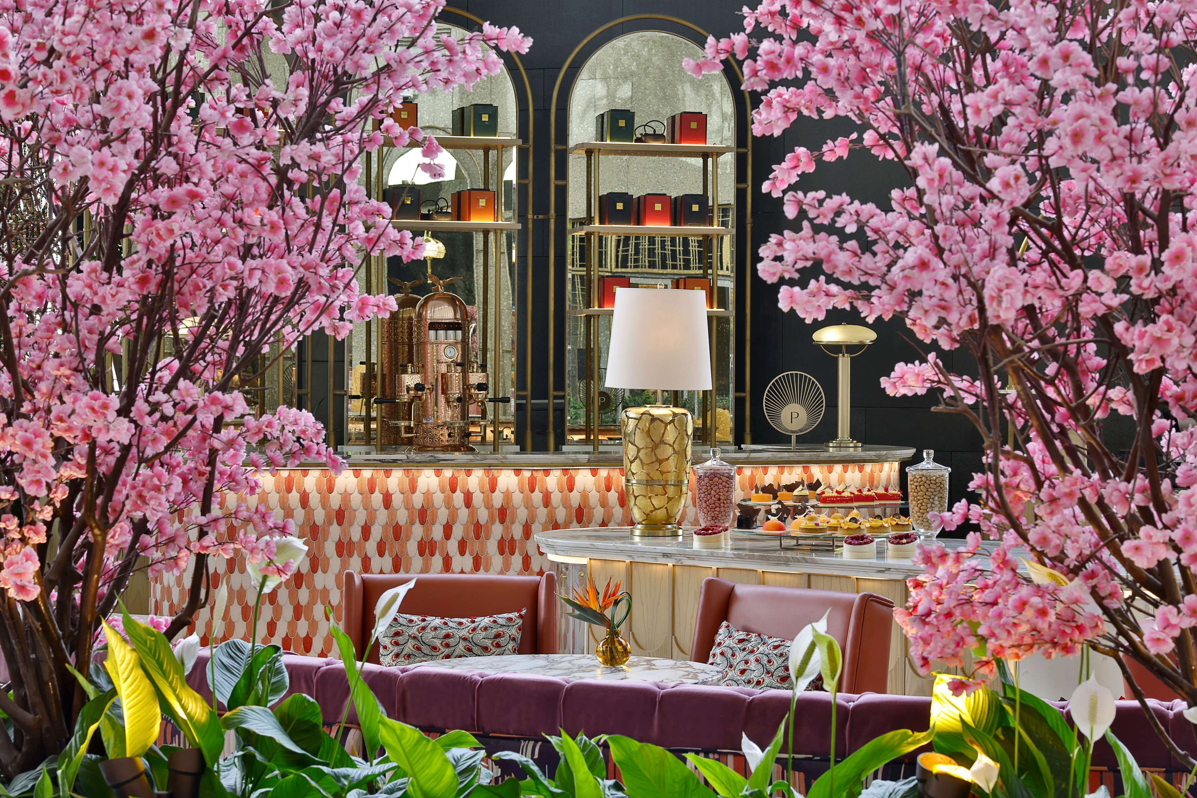 Un restaurante con zona de bar, asientos y un fondo decorativo de flores rosadas.