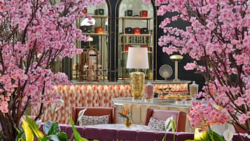Un restaurante con zona de bar, asientos y un fondo decorativo de flores rosadas.