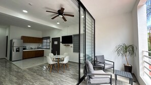 A modern kitchen with a refrigerator, wooden cabinets, and a dining area with a table and chairs.