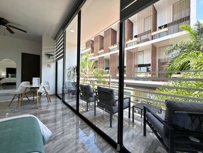 A modern hotel room with a balcony, a dining area, and a view of the building's exterior. - BORÉNA Hotel Boutique (Playa del Carmen)