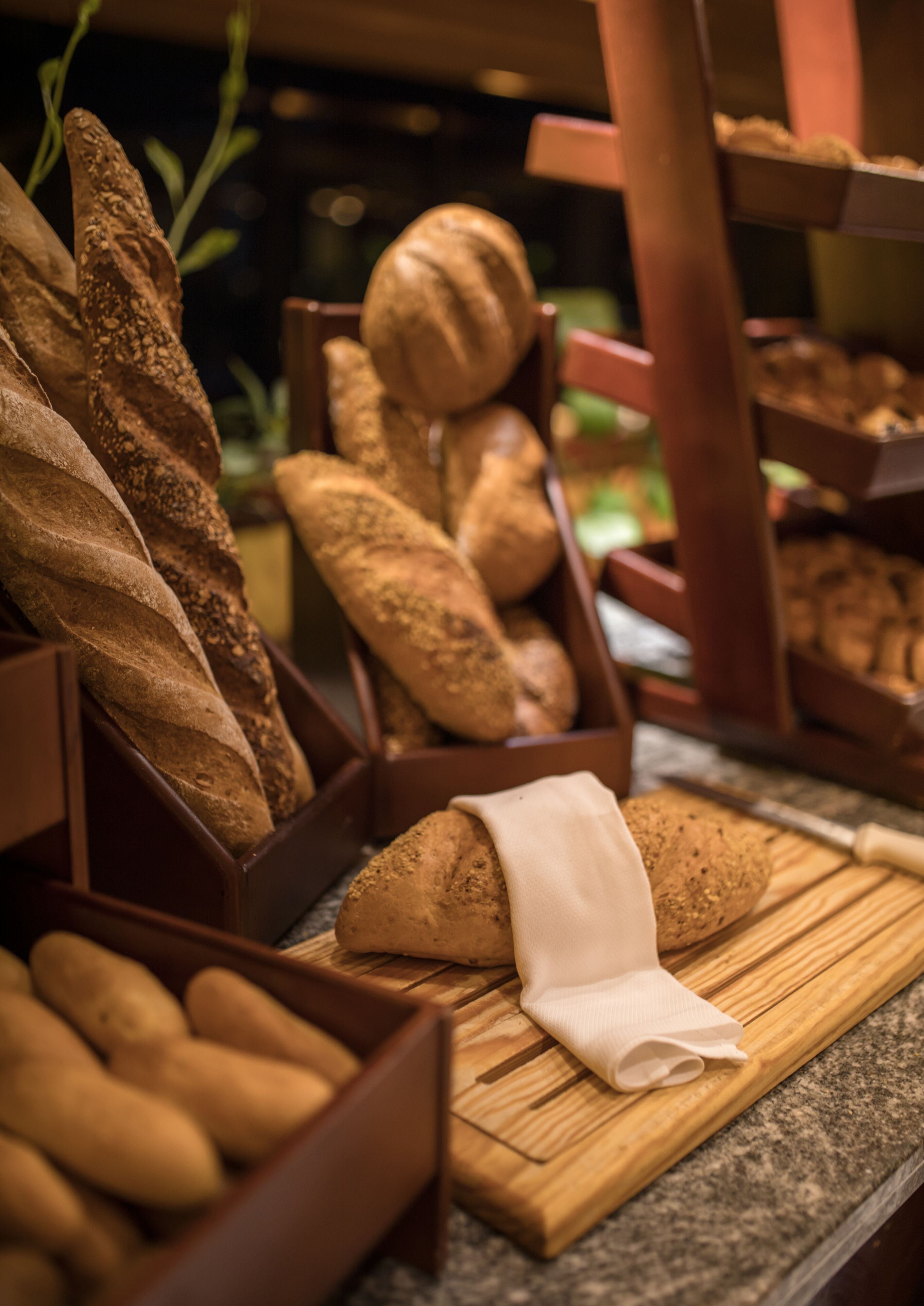 A variety of breads displayed in wooden baskets on a countertop.