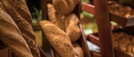 A variety of breads displayed in wooden baskets on a countertop.