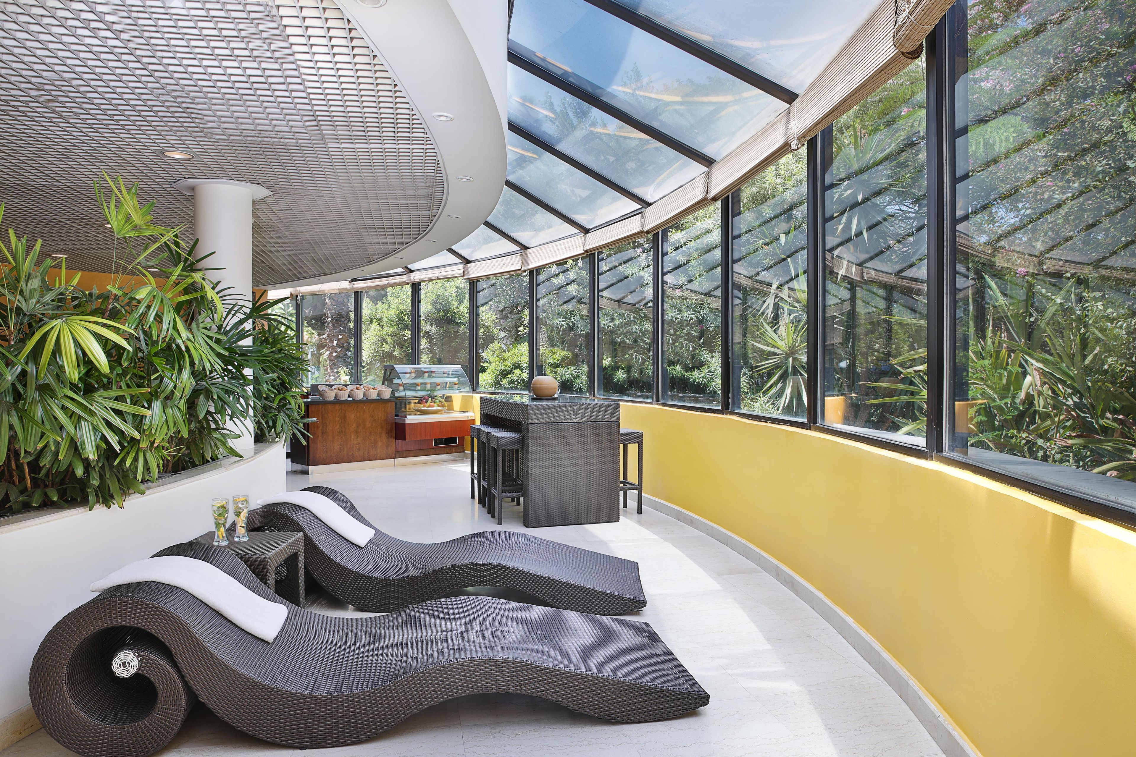 Un interior moderno con techo curvo, ventanas amplias y una zona de estar con mobiliario de mimbre.