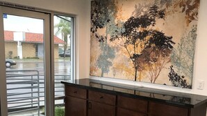 A kitchen with wooden cabinets, a large window, and a mural on the wall. - Castaway Motel (Orange)