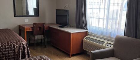 A hotel room with two beds, a desk with a computer, a chair, and a sofa.