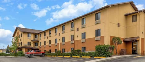 A multi-story hotel with a flat roof and a parking lot in front.