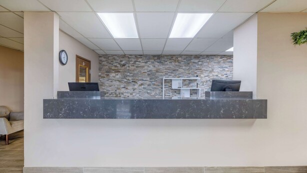 A reception area with a marble counter, a clock, and a mosaic wall. - Super 8 by Wyndham Butte MT (Butte)