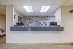Un área de recepción con mostrador de mármol, un reloj y una pared con mosaicos.